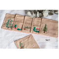 Set of five beige linen coasters with embroidered Christmas designs, including a pine tree and holly — hand-embroidered by The Thread Nest