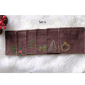 Set of six brown linen coasters with embroidered Christmas designs — hand-embroidered by The Thread Nest