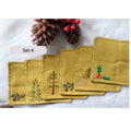 Set of six yellow linen coasters with embroidered Christmas designs, including a pine tree — hand-embroidered by The Thread Nest