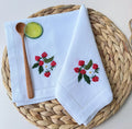 Two white linen napkins with embroidered red strawberries and white flowers — hand-embroidered by The Thread Nest