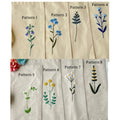 Eight different embroidery patterns shown on beige linen — hand-embroidered by The Thread Nest