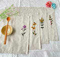 Beige linen placemats with embroidered floral designs — hand-embroidered by The Thread Nest