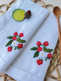 Two white linen napkins with embroidered strawberry designs — hand-embroidered by The Thread Nest
