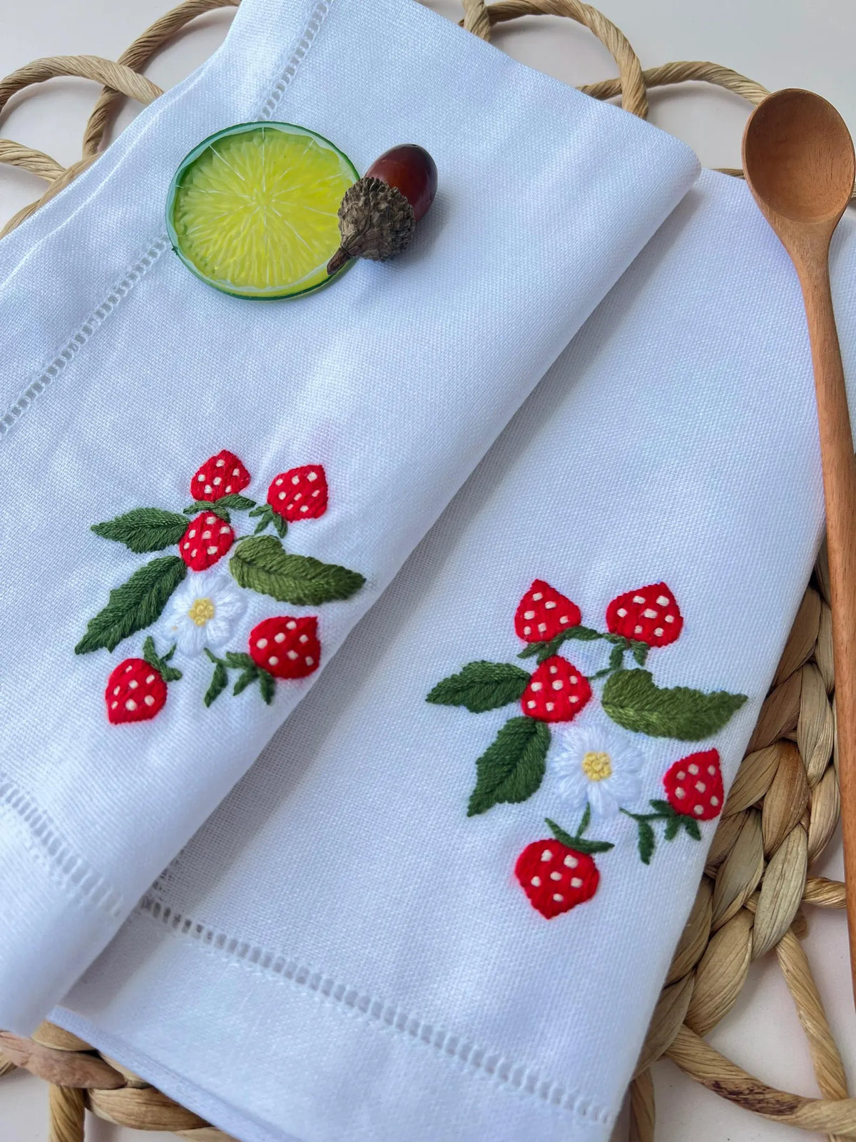 Two white linen napkins with embroidered strawberry designs — hand-embroidered by The Thread Nest
