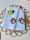Two white linen napkins with embroidered strawberry designs — hand-embroidered by The Thread Nest