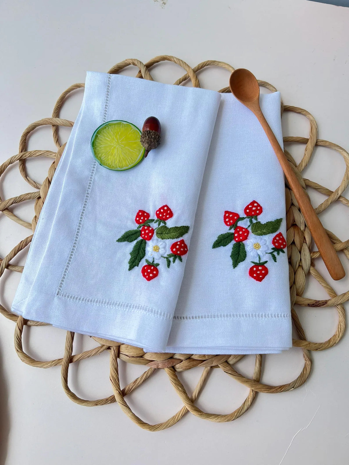 Two white linen napkins with embroidered strawberry designs — hand-embroidered by The Thread Nest