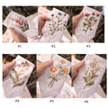 A collection of six white linen handkerchiefs, each with a different floral embroidery — hand-embroidered by The Thread Nest