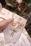 A white linen napkin with an embroidered floral design — hand-embroidered by The Thread Nest