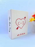 A cream-colored photo album with a red embroidered heart and Our Love Story on the spine — hand-embroidered by The Thread Nest