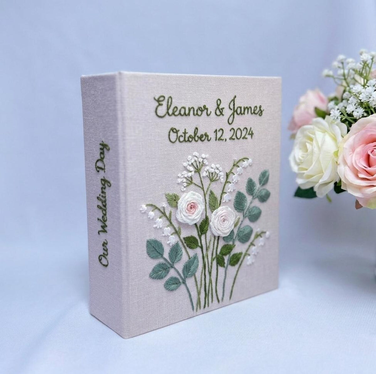 A light beige wedding photo album with embroidered floral details — hand-embroidered by The Thread Nest