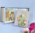 A beige photo album with an embroidered floral design, open on a photograph — hand-embroidered by The Thread Nest