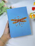 Dragonfly Embroidered Journal by The Thread Nest, pale blue linen cover with a hand-embroidered dragonfly, photo 1