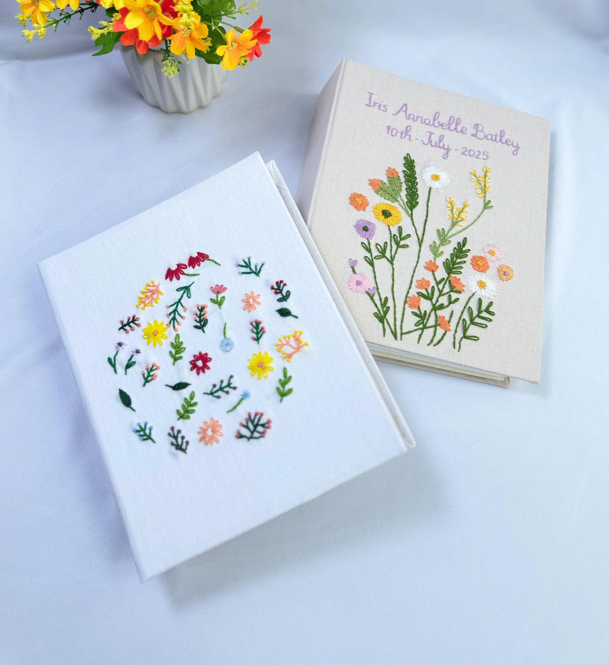 Two rectangular fabric-covered albums — hand-embroidered by The Thread Nest