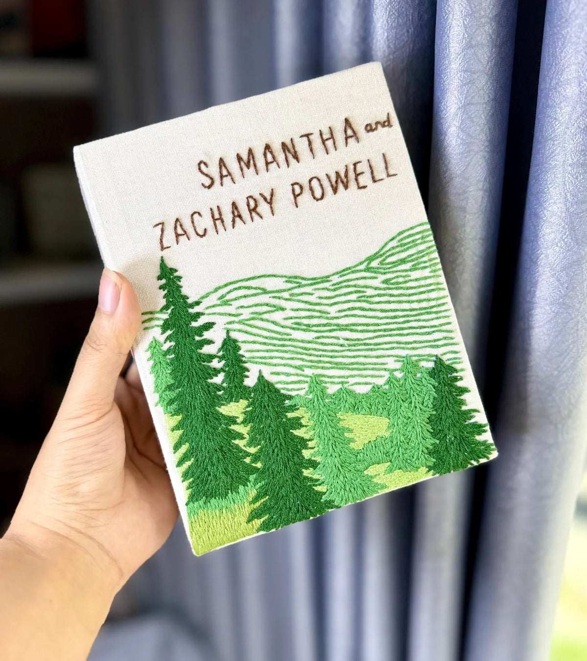 A personalized cover with embroidered names, a green forest and mountains — hand-embroidered by The Thread Nest