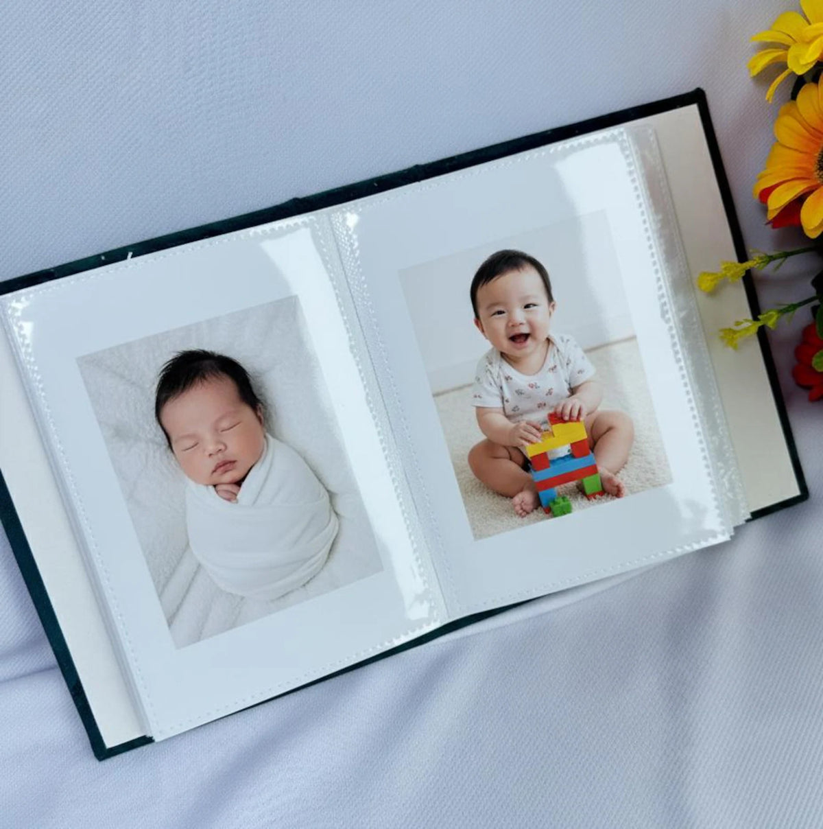 An open photo album with two newborn photographs in the sleeves
