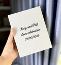 A white canvas board with printed names and a wedding date — hand-embroidered by The Thread Nest