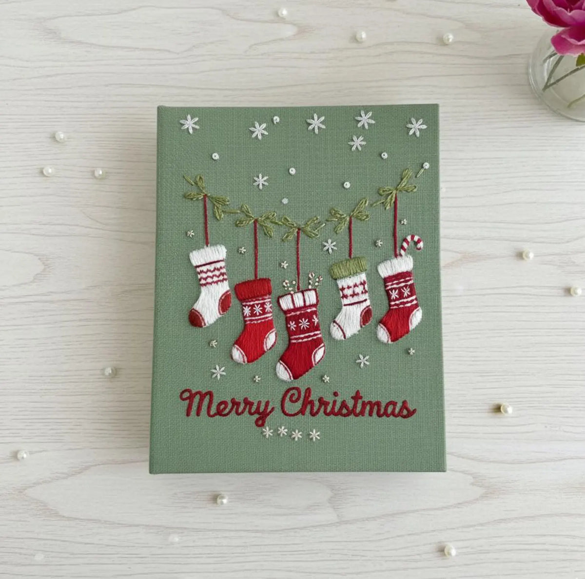 A green Christmas piece with five embroidered hanging stockings — hand-embroidered by The Thread Nest