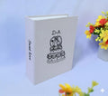 A light beige photo album with a black line drawing of a three-tiered wedding cake — hand-embroidered by The Thread Nest