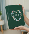 A dark green keepsake box with a heart of embroidered flowers and two initials — hand-embroidered by The Thread Nest