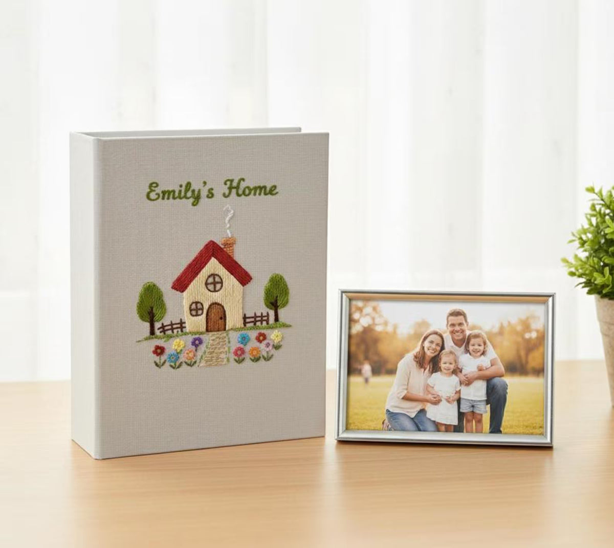 A light gray photo album with an embroidered house and a stitched line of text — hand-embroidered by The Thread Nest