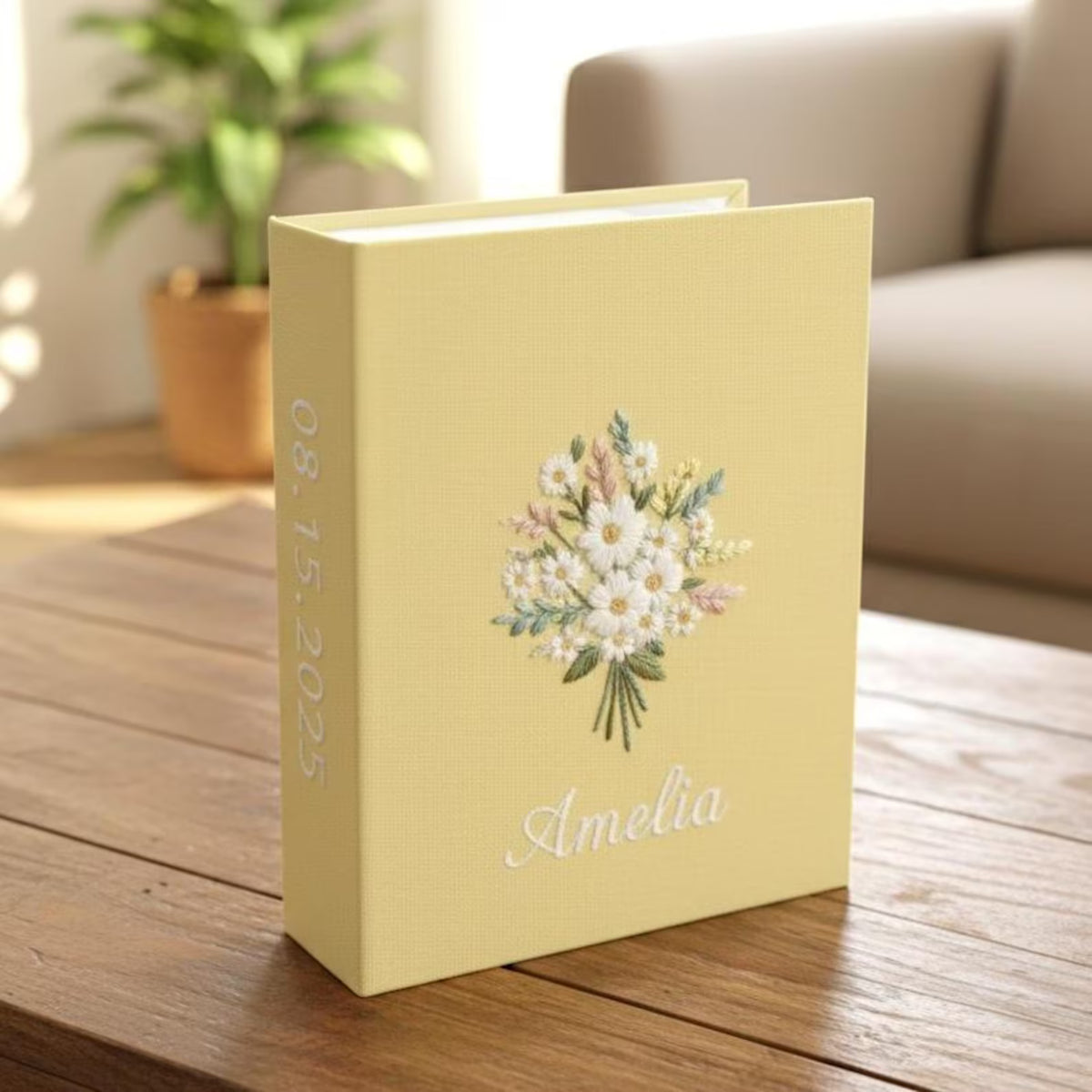 A yellow photo album with an embroidered floral bouquet, a name and a date — hand-embroidered by The Thread Nest