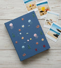 A blue journal with embroidered jellyfish, starfish and coral — hand-embroidered by The Thread Nest