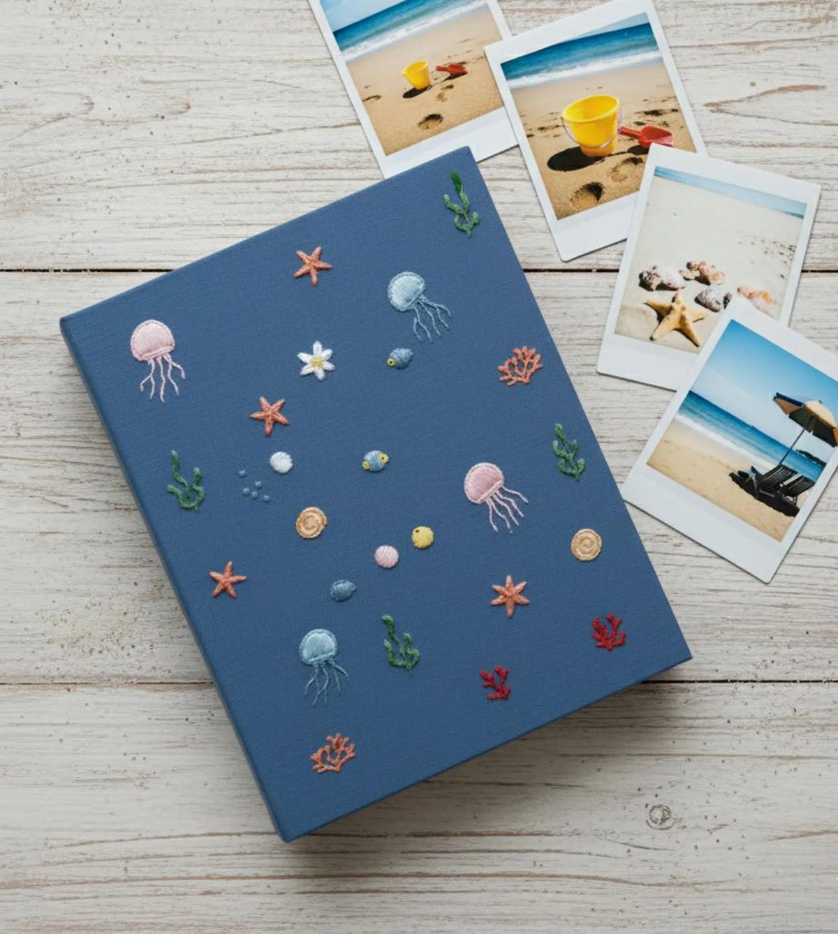 A blue journal with embroidered jellyfish, starfish and coral — hand-embroidered by The Thread Nest