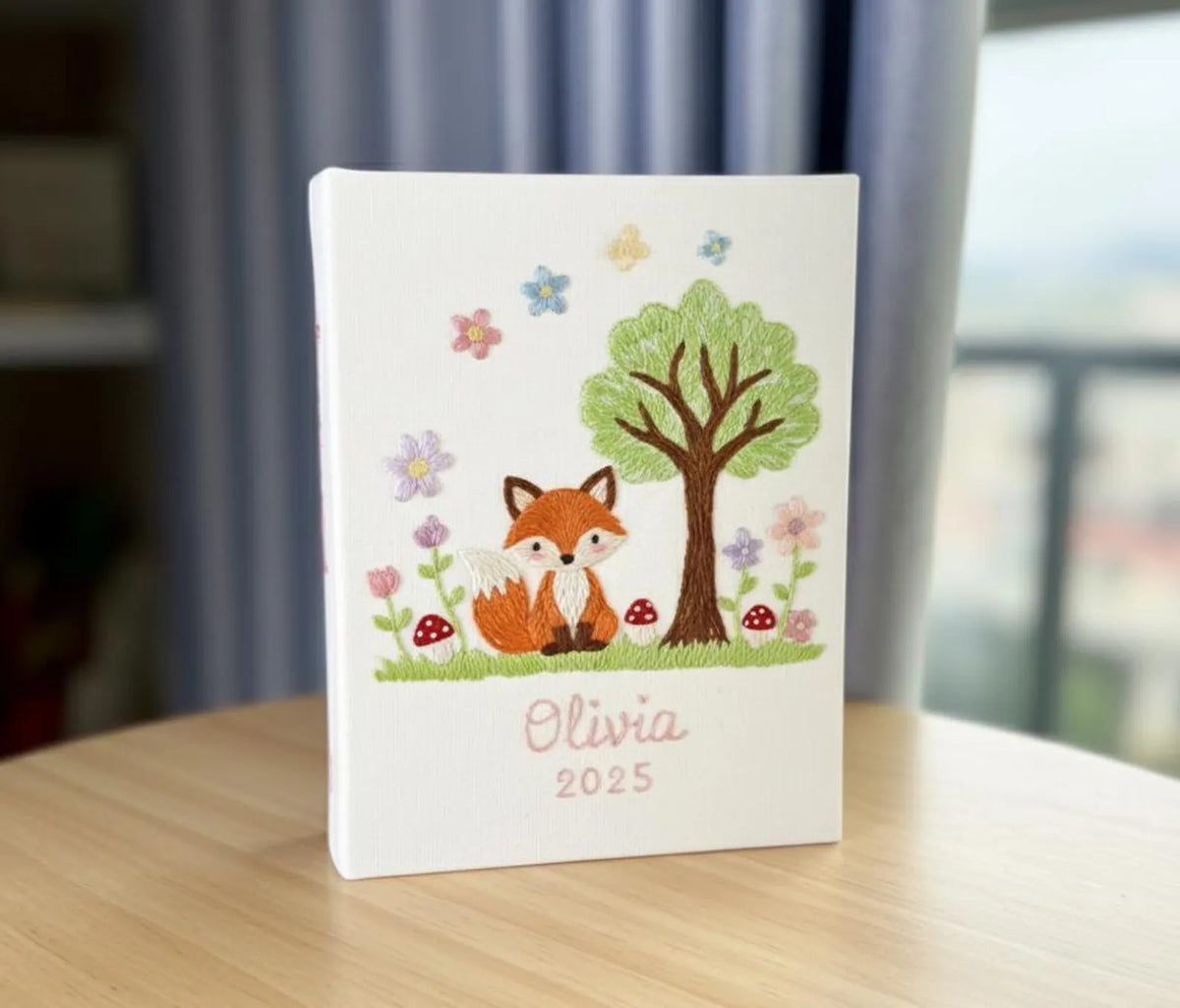 An embroidered white canvas with a fox, a tree, flowers and mushrooms — hand-embroidered by The Thread Nest