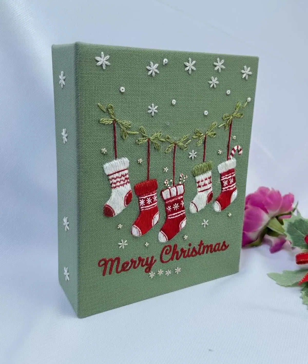 A green Christmas piece with embroidered snowflakes and hanging stockings — hand-embroidered by The Thread Nest