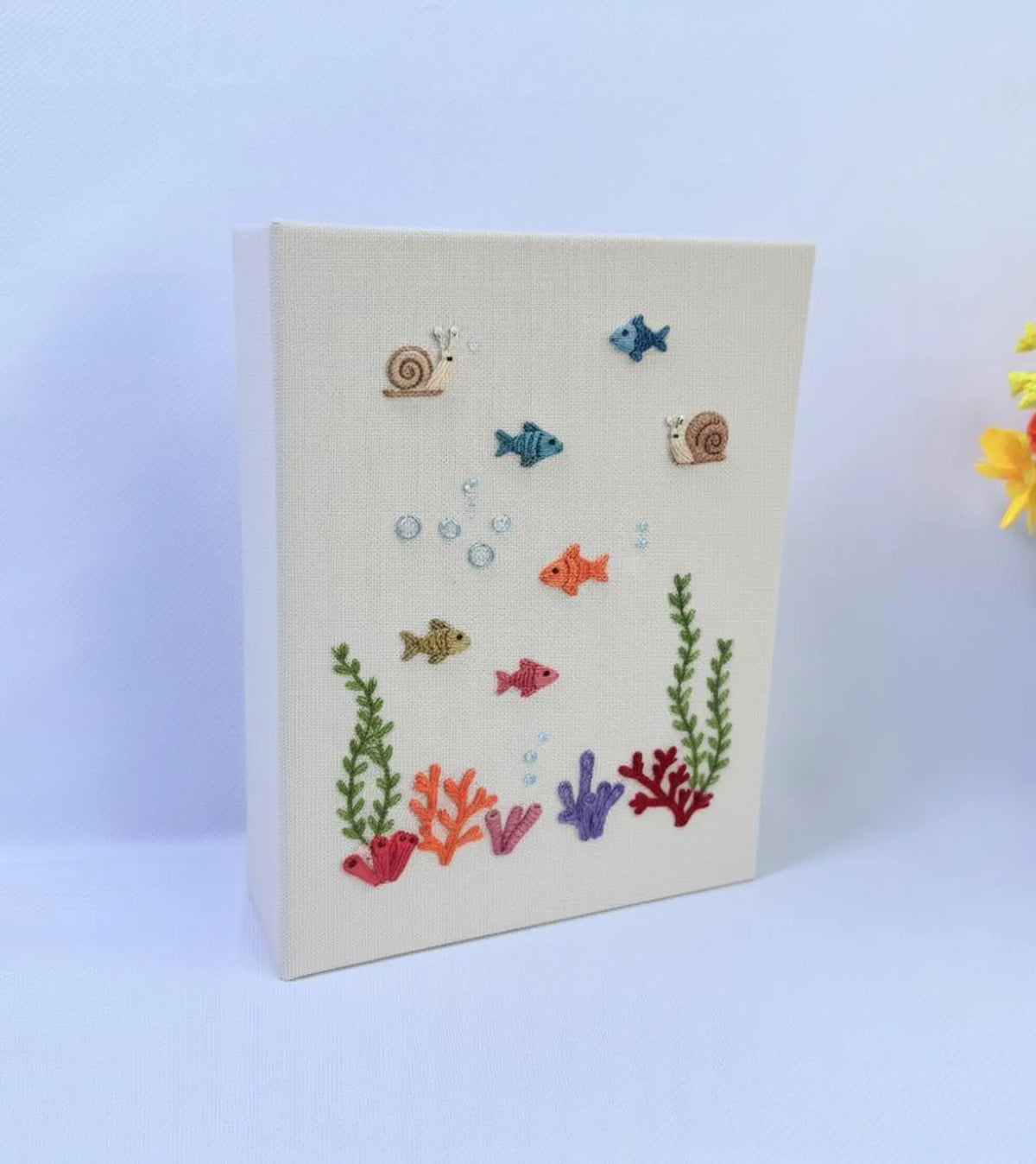 A cream-colored canvas with an embroidered underwater scene — hand-embroidered by The Thread Nest