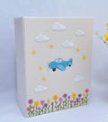 A light beige photo album with a central embroidered airplane — hand-embroidered by The Thread Nest