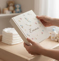 A white hardcover book with an embroidered goose wearing a blue hat and scarf — hand-embroidered by The Thread Nest