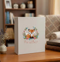 A light beige photo album with an embroidered fox inside a floral wreath — hand-embroidered by The Thread Nest