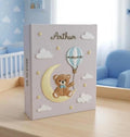A light gray baby memory book with a teddy bear on a crescent moon — hand-embroidered by The Thread Nest