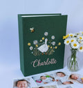 A dark green photo album with an embroidered goose, flowers and a bee — hand-embroidered by The Thread Nest