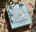 A light blue photo album with an embroidered crescent moon, a bear and a floral wreath — hand-embroidered by The Thread Nest