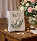 A linen-covered wedding guest book with embroidered floral details — hand-embroidered by The Thread Nest