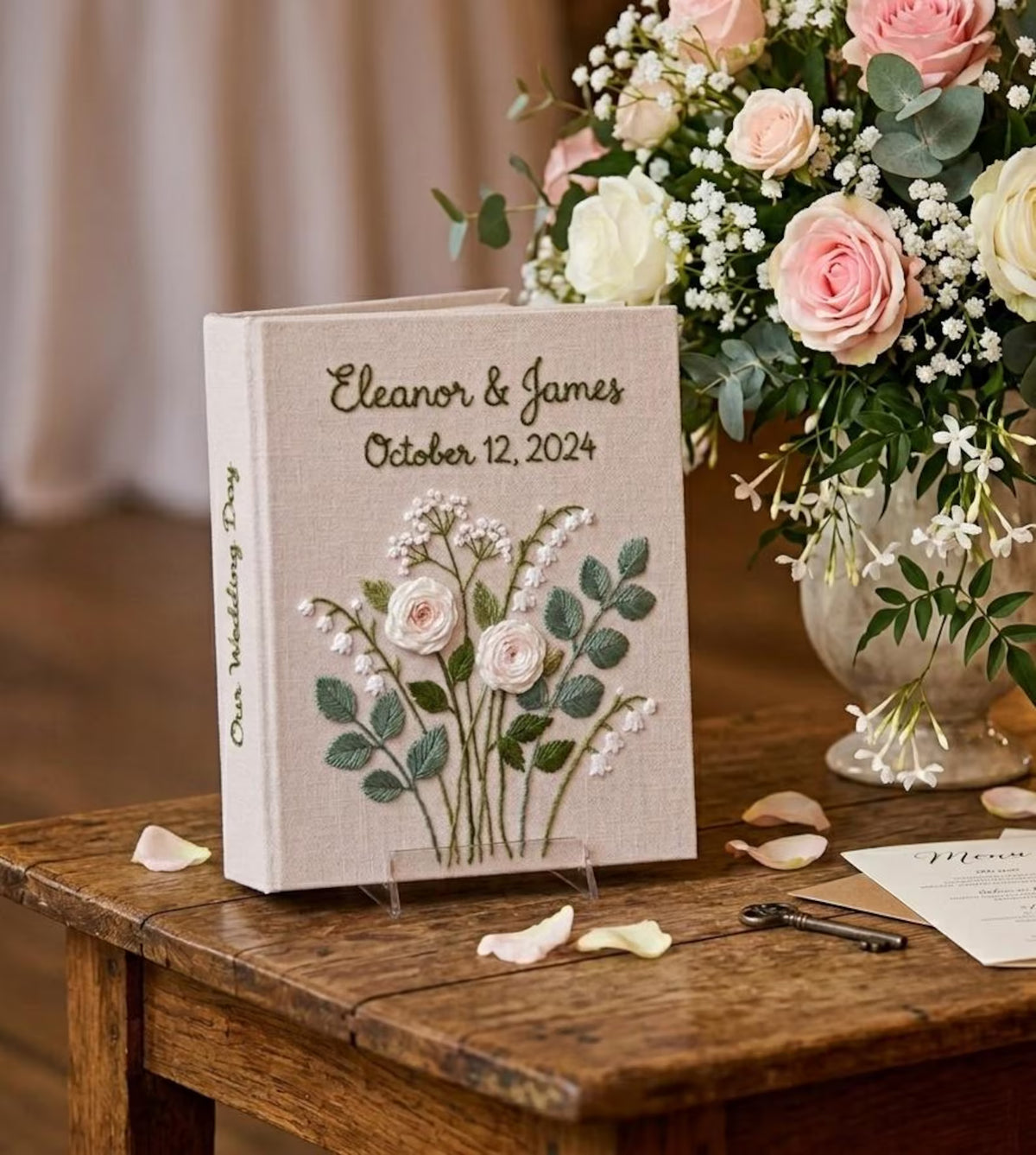 A linen-covered wedding guest book with embroidered floral details — hand-embroidered by The Thread Nest