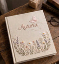 A beige journal with a name in cursive and a butterfly above it — hand-embroidered by The Thread Nest