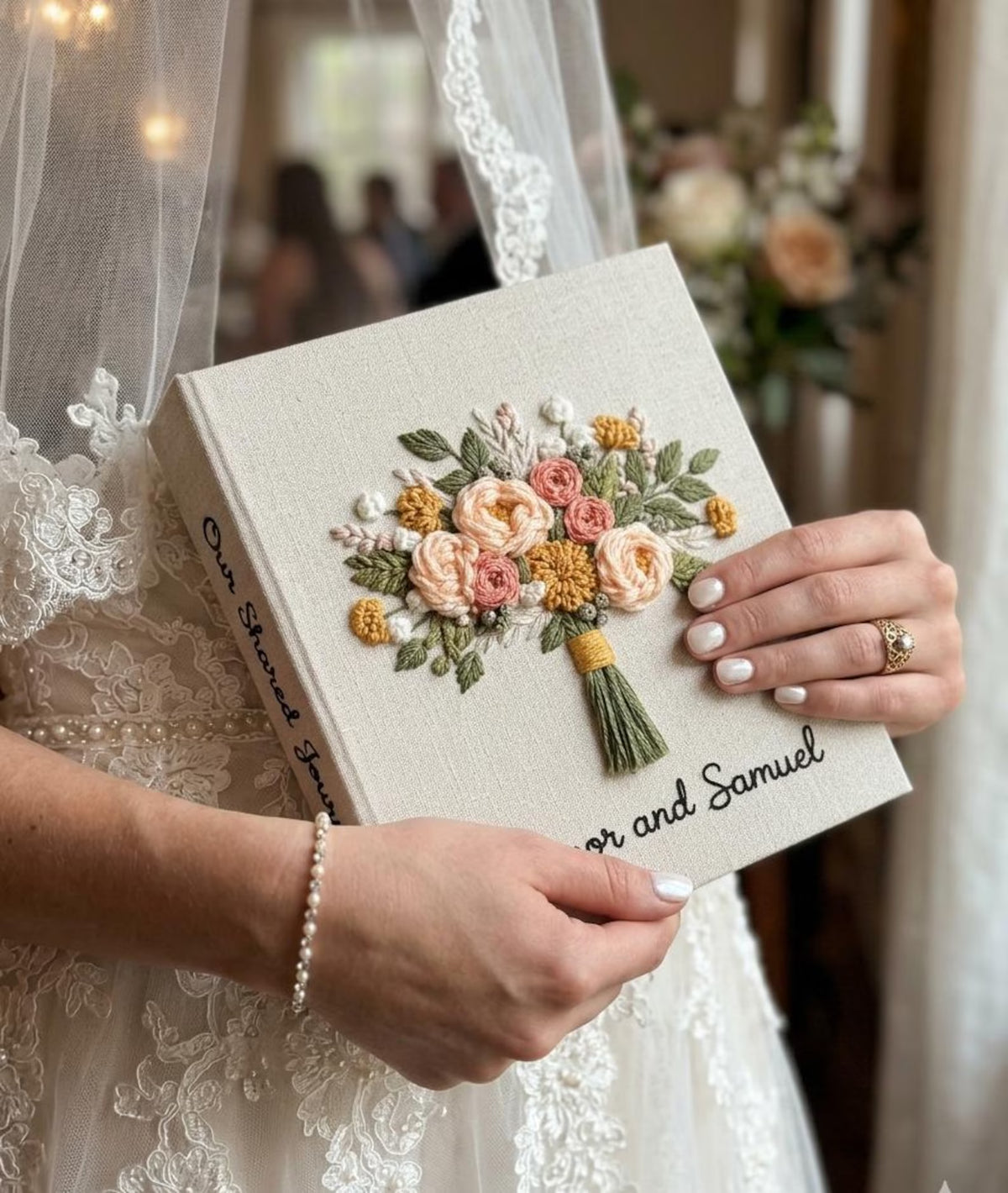 A cream-colored journal with embroidered floral bouquet in peach, yellow, and green — hand-embroidered by The Thread Nest
