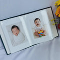 An open photo album with two baby photographs in the sleeves