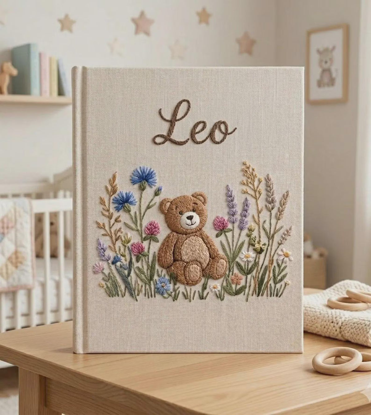 A beige book with a central brown teddy bear surrounded by flowers — hand-embroidered by The Thread Nest