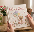A square off-white book with an embroidered teddy bear and a stitched name — hand-embroidered by The Thread Nest