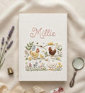 A white hardcover book with embroidered chickens, a duck and chicks in a garden — hand-embroidered by The Thread Nest