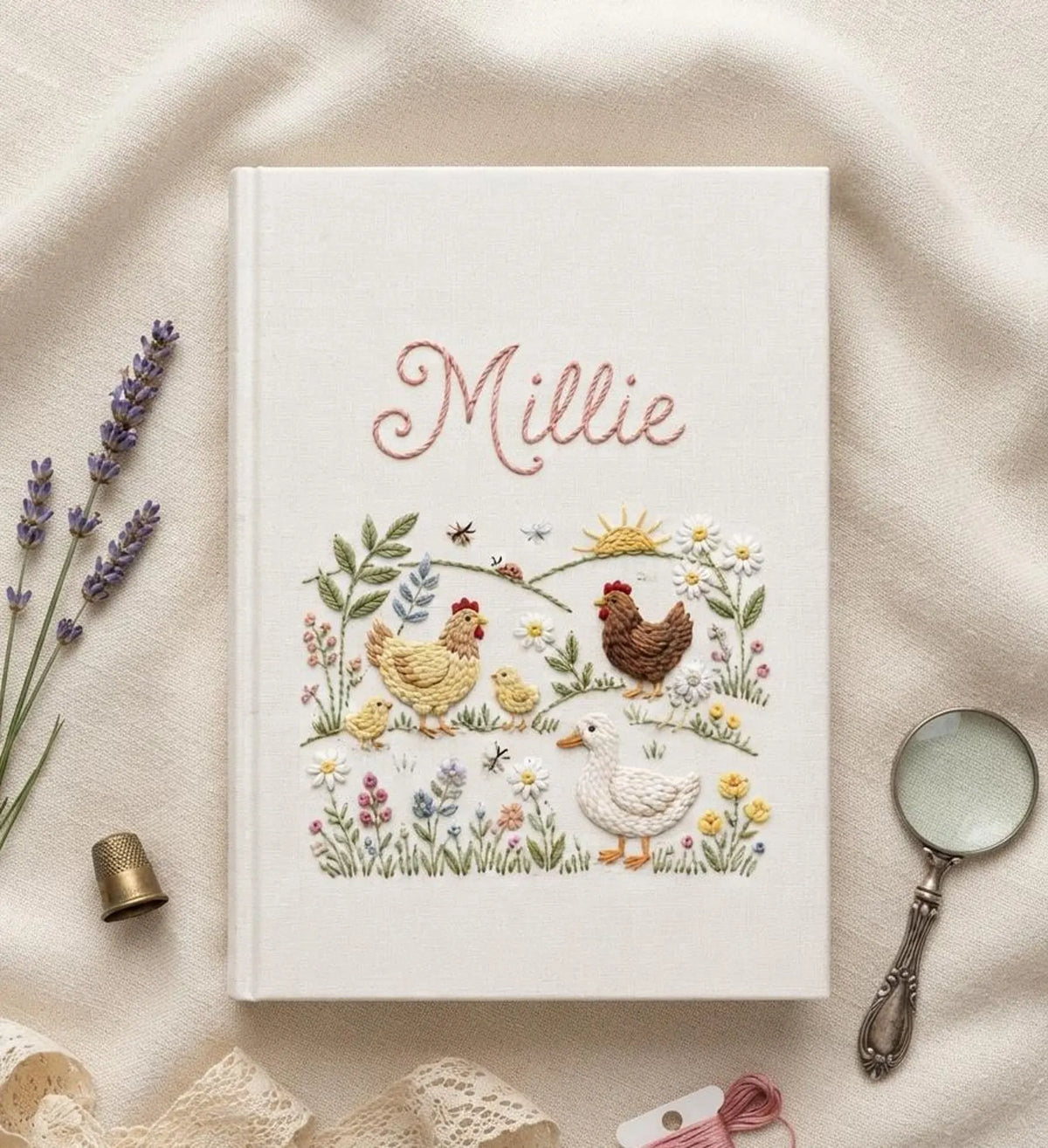 A white hardcover book with embroidered chickens, a duck and chicks in a garden — hand-embroidered by The Thread Nest